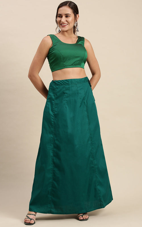 Woman wearing a green outfit with a top and petticoat inskirt on a beige background