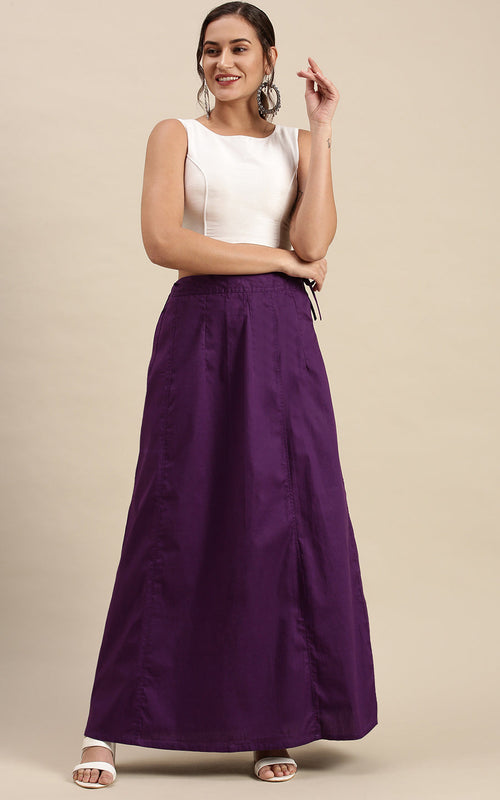 Woman wearing a white top and purple petticoat inskirt on a beige background
