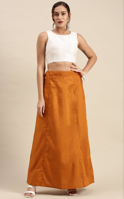 Woman wearing a white sleeveless top and mustard skirt on a beige background