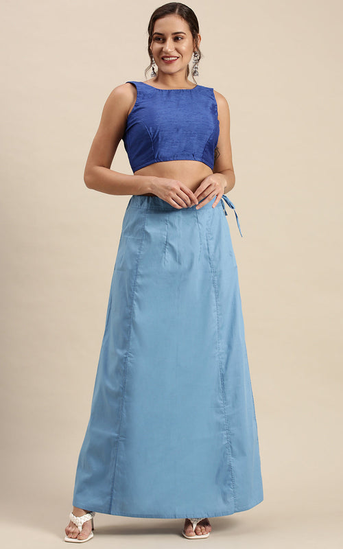 Woman wearing a blue top and petticoat inskirt on a beige background
