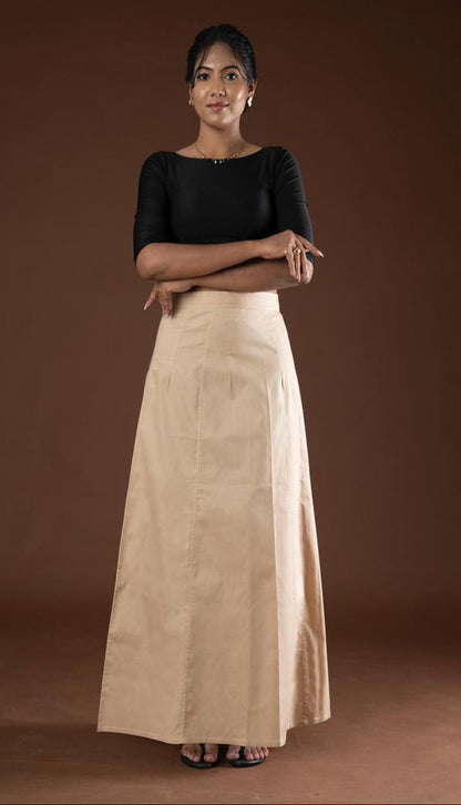 Woman wearing a black top and beige petticoat inskirt against a brown background