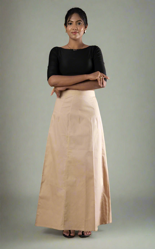 Woman wearing a black top and beige petticoat in-skirt against a grey background