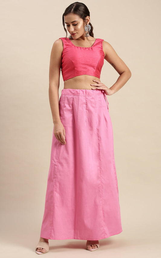 Woman wearing a pink outfit with a top and bubblegum pink petticoat in-skirt on a beige background