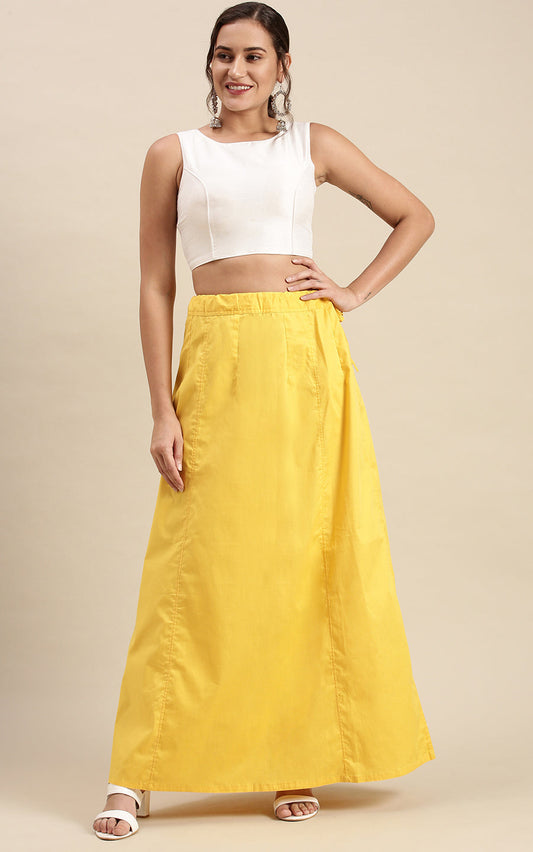 Woman wearing a white sleeveless top and yellow petticoat inskirt on a beige background