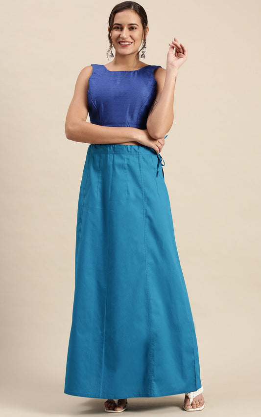 Woman wearing a blue sleeveless top and petticoat inskirt on a beige background