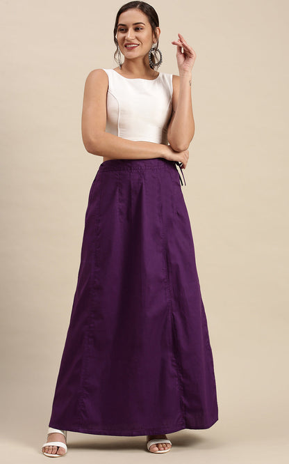 Woman wearing a white top and purple petticoat inskirt on a beige background