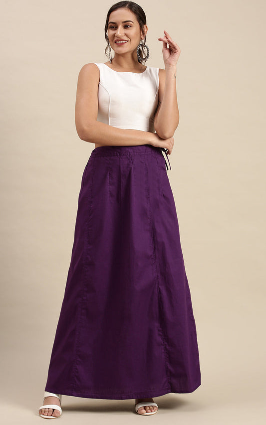 Woman wearing a white top and purple petticoat inskirt on a beige background