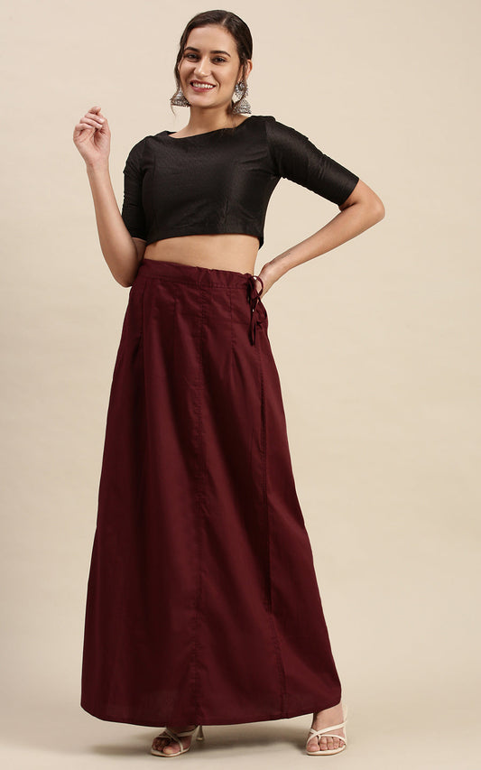 Woman wearing a black top and brown petticoat inskirt on a beige background
