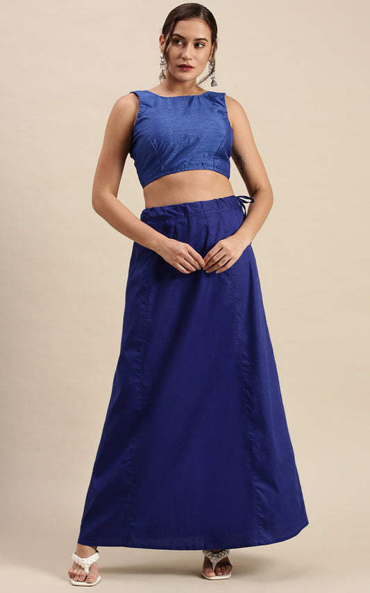 Woman wearing a blue outfit with a top and blue petticoat inskirt on a beige background