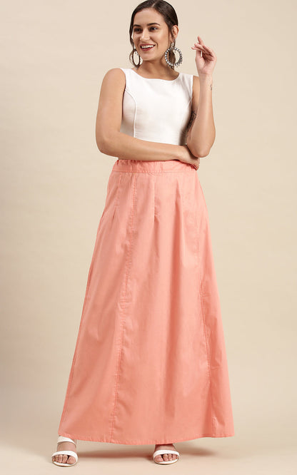 Woman wearing a white top and peach petticoat inskirt on a beige background