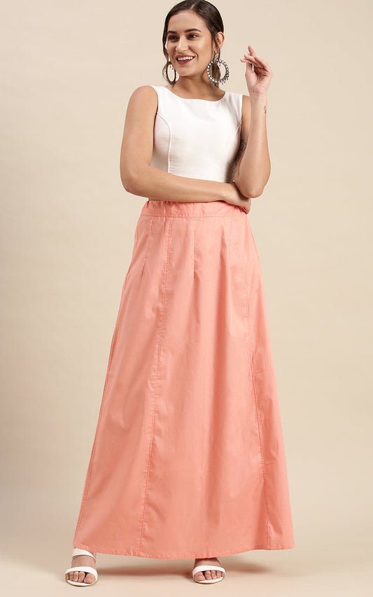 Woman wearing a white top and peach petticoat inskirt on a beige background