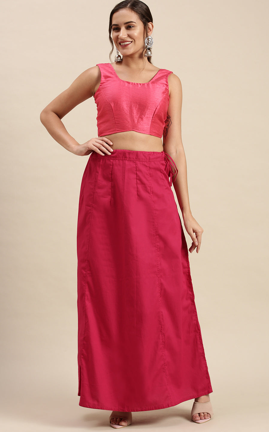 Woman wearing a pink top and rose petticoat inskirt on a beige background