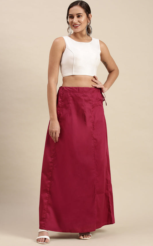 Woman wearing a white top and rose inskirt on a beige background