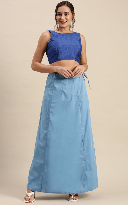 Woman wearing a blue top and petticoat  inskirt on a beige background