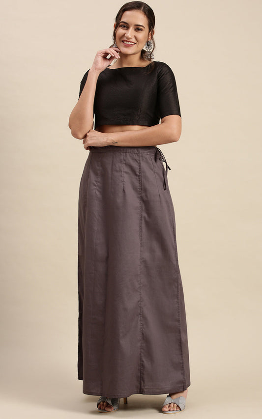 Woman wearing a black top and gray petticoat inskirt on a beige background