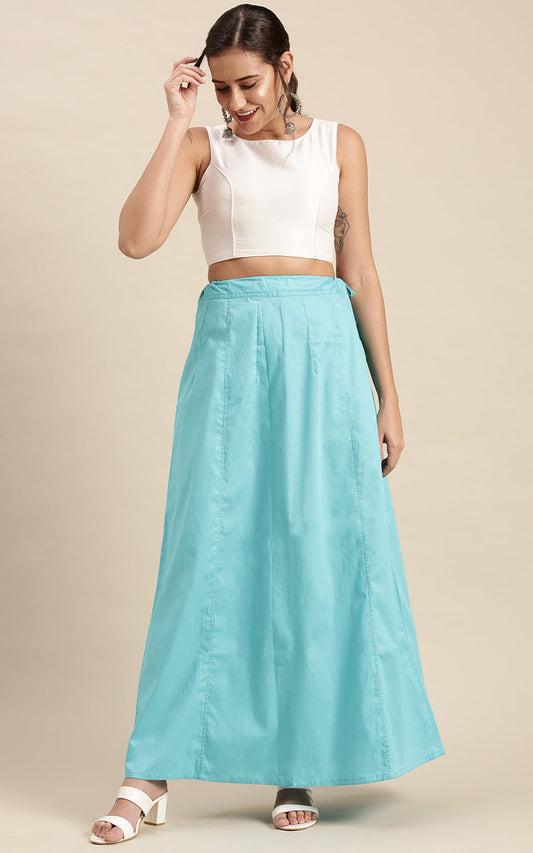 Woman wearing a white top and turquoise blue petticoat inskirt on a beige background